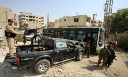 Des soldats syriens protègent un bus qui évacue des habitants de Daraya, près de Damas, le 26 août 2016