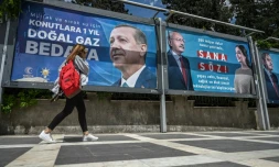 Une femme passe devant les affiches du président turc Recep Tayyip Erdogan (gauche) et de son principal adversaire à l'élection présidentielle Kemal Kiliçdaroglu (droite), le 28 avril 2023 à Sanliurfa, dans le sud-est de la Turquie