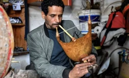 L'artisan tunisien Khaled ben Khemis souffle dans un mezoued dans un atelier près de Tunis, le 24 mai 2023 ( AFP / FETHI BELAID )
