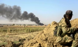 Un combattant syrien proturc regarde au loin la fumée s'élever de la ville frontalière de Ras al-Aïn, dans le nord de la Syrie, bombardée par les forces turques, le 12 octobre 2019