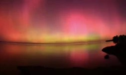 Une aurore australe vue au dessus des eaux du lac Ellesmere, prÚs de Christchurch en Nouvelle Zélande le 11 mai 2024 ( AFP / Sanka Vidanagama )