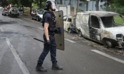 Un policier à proximité de véhicules calcinés après une quatrième nuit consécutive d'émeutes causées par la mort de Nahel, le 1er juillet 2023 à Nanterre ( AFP / CHARLY TRIBALLEAU )