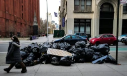 Une femme devant un tas de poubelles Ă Manhattan, New York le 19 mars 2024