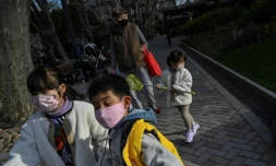 Des enfants, portant un masque de protection contre le coronavirus, jouent dans un parc à Shanghaï, le 17 mars 2020