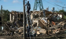 Des électriciens ukrainiens réparent le réseau électrique devant une maison privée détruite où un adolescent de 14 ans a été tué lors d'une attaque aérienne à Vyshgorod, dans la région de Kiev, le 30 septembre 2026