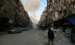 Un homme marche avec des béquilles dans une rue de la ville de Douma, dans la Ghouta orientale, aprÚs un bombardement du régime, le 23 février 2018