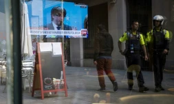 Des policiers catalans marchent devant un bar à Barcelone, dans lequel est diffusé une conférence de presse depuis Bruxelles du président catalan destitué par Madrid, Carles Puigdemont, le 31 octobre 2017