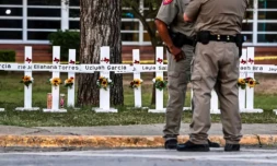 Des policiers se tiennent le 26 mai 2022 devant un mémorial de fortune pour les victimes de la fusillade dans l'école primaire Robb d'Uvalde au Texas ( AFP / CHANDAN KHANNA )