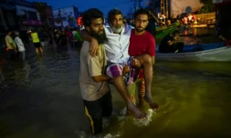 De jeunes hommes portent une personne ùgée dans une rue inondée de Wellampitiya, dans les faubourgs de Colombo, la capitale du Sri Lanka, le 30 novembre 2025 ( AFP / Ishara S. KODIKARA )