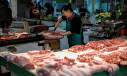 Une vendeuse coupe du porc sur un marché de Hangzhou, dans la province du Zhejiang, dans l'est de la Chine, le 10 avril 2025