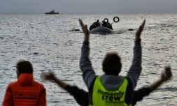 Des militants d'une ONG guident des migrants arrivant à bord d'un bateau arrivant de Turquie à Mytilène sur l'île grecque de Lesbos le 19 février 2016