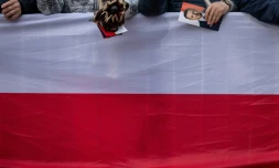Une femme tient un tract de campagne du maire de Varsovie et candidat à la présidence, Rafal Trzaskowski, alors qu'elle et d'autres partisans de M. Trzaskowski se rassemblent sur le marché principal de Skierniewice, en Pologne, le 16 mai 2025