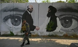 Un soldat passe devant une fresque murale dépeignant l'émissaire américain pour l'Afghanistan Zalmay Khalilzad et le co-fondateur des talibans Mullah Abdul Ghani Baradar le 31 juillet 2020 à Kaboul    