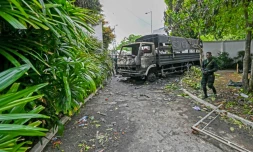 Des soldats sri-lankais montent la garde le 10 mai 2022 près d'un camion incendié par des manifestants devant la résidence du Premier ministre démissionnaire Mahinda Rajapaksa