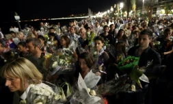 Une chaßne humaine déplace les bouquets déposés sur la Promenade des Anglais en hommage aux victimes de l'attentat du 14 juillet vers le front de mer à Nice le 18 juillet 2016