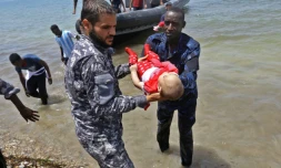 Le corps d'un des trois bénés repêchés vendredi après le naufrage d'une embarcation est porté par des membres des forces de sécurité libyennes, le 29 juin 2018 à al-Hmidiya