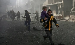 Un homme syrien court pour sauver un enfant aprÚs des bombardements du régime syrien contre la ville rebelle de Hammouriyé le 19 février 2018
