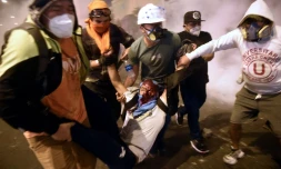 Des manifestants portent un blessé lors de heurts avec la police au cours d'un rassemblement de soutien au président Vizcarra, le 14 novembre 2020 à Lima, au Pérou