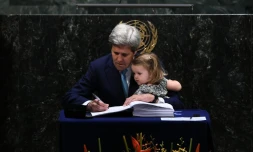 Le secrétaire d'Etat américain John Kerry signe l'accord sur le climat tenant sa petite-fille, à l'ONU à New York, le 22 avril 2016 