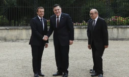 Le président Emmanuel Macron et le chef du gouvernement de Tripoli Fayyez al-Sarraj se serrent la main, accompagnés du ministre français des Affaires étrangères Jean-Yves Le Drian, à La Celle-Saint-Cloud, près de Paris, le 25 juillet 2017