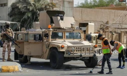 Des soldats montent la garde à l'entrée de la Zone verte pendant que des employés municipaux nettoient les rues après le retrait des partisans du leader chiite Moqtada Sadr, le 30 août 2022 à Bagdad, en Irak