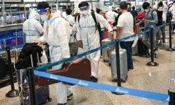 Des passagers vêtus de tenue de protection font la queue à l'enregistrement à l'aéroport de Kuala Lumpur, à Sepang, le 29 novembre 2021