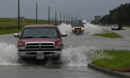 Des véhicules roulent sur une route inondée dans l'agglomération de Houston, le 29 août 2017