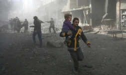 Un secouriste évacue un enfant tiré des gravats d'un immeuble, après une frappe aérienne, à Hammouriyé, dans la partie rebelle de la Ghouta orientale, le 19 février 2018