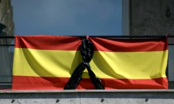 Le drapeau espagnol orné d'un ruban noir, pour les malades et les morts dûs au Covid-19, sur un balcon à Madrid le 8 avril 2020