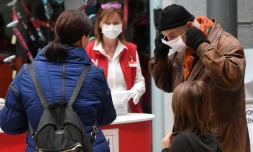 Des employés distribuent des masques aux clients d'un supermarché à Vienne le 1er avril 2020