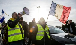 Des participants à des convois anti-pass, portant des gilets jaunes, agitent des drapeaux sur une route dans le nord de la France, le 13 février 2022