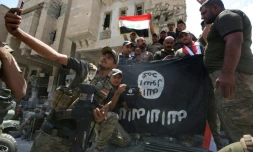 Des membres des forces de sécurité irakiennes posent autour d'un drapeau à l'envers de l'Etat islamique, le 8 juillet 2017 à Mossoul