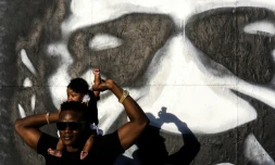 Un Américain lève le poigt de sa fille devant le mémorial improvisé en l'honneur de George Floyd, à Minneapolis le 25 mai 2021