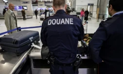 Des douaniers inspectent les bagages de passagers à l'aéroport de Roissy-Charles-de-Gaulle, au nord de Paris, le 21 mars 2025 
