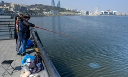 Des pêcheurs au bord de la mer Caspienne à Bakou, où des traces de pétrole sont visibles dans l'eau, le 22 mars 2019