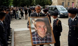 Un employé des services funéraires passe entre des soldats du 13e bataillon de chasseurs alpins de Chambéry avec un portrait d'Arthur Noyer, sur le parvis de la cathédrale Saint-Etienne à Bourges, le 7 septembre 2018, jour de ses funérailles