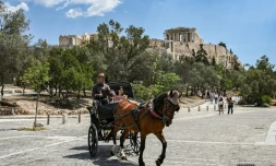 Des touristes en calèche passent devant la colline de l'Acropole, le 29 mai 2025 à Athènes