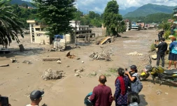 Des habitants observent des maisons partiellement submergées dans des eaux boueuses à la suite d'inondations soudaines survenues à Trishuli Bazar, dans le district de Nuwakot au Népal, le 26 août 2026.