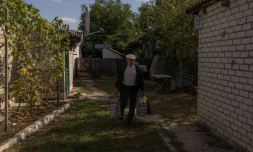 SerguiĂŻ, chargĂ© de deux gros sacs, quitte sa maison pour ĂȘtre Ă©vacuĂ© par les membres de la Croix-Rouge ukrainienne, le 28 septembre 2023 Ă Bogouslavka, dans l'est de l'Ukraine