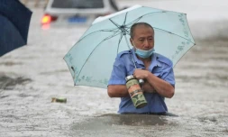 Un homme avance dans une rue inondée de Zhengzhou, placée en alerte rouge aprÚs des orages violents qui se sont abattus sur cette métropole du centre de la Chine, le 20 juillet 2021