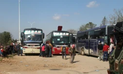 Un combattant rebelle devant des bus transportant des personnes évacuées la veille de localités syriennes loyalistes, le 15 avril 2017 à Rachidine, une banlieue rebelle à l'ouest d'Alep