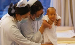 Des infirmières chinoises prennent soin d'un bébé pendant que sa mère se repose, au centre Xiyuege ("Foyer du mois de la chance") à Pékin, le 13 décembre 2016