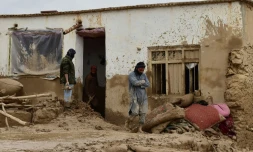 Des Afghans devant une maison ravagée par les crues subites qui ont touché le nord-est de l'Afghanistan, le 11 mai 2024 à Laqiha, dans la province de Baghlan