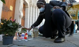 Une femme allume une bougie devant la basilique Notre-Dame à Nice lors d'un hommage aux victimes de l'attentat, le 30 octobre 2020 
