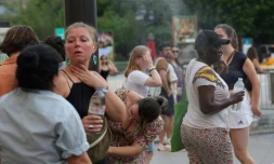 Des personnes se rafraîchissent en traversant un fin brouillard d'eau dans le centre de Paris le 21 juin 2025