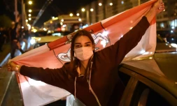 Une femme masquée portant l'ancien drapeau du Bélarus lors d'une manifestation d'opposition à Minsk, le 13 août 2020