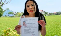 Odile Dussart, évacuée de Saïgon alors qu'elle n'était qu'un bébé de 11 mois, quelques semaines avant la fin de la guerre du Vietnam il y a 50 ans, montre son certificat de nationalité vietnamienne dans sa nouvelle maison à Hoi An, le 12 avril 2025