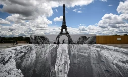 Une femme saute sur l'esplanade du Trocadéro, en face de la Tour Eiffel, au-dessus d'un trompe-l'oeil de l'artiste français de street-art JR, le 19 mai 2021 à Paris