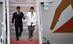 Les anciens champions olympiques Tadahiro Nomura (gauche) et Saori Yoshida (C) amènent la flamme olympique à la base militaire de Matsushima le 20 mars 2020