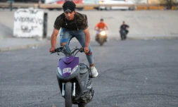 De jeunes Irakiens effectuent des cascades avec leurs scooters pour se divertir, à Bagdad le 6 août 2021